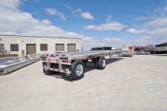 Flatbed trailer outside by commercial building, second view from the rear