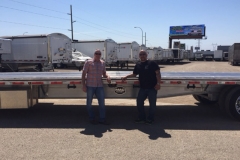 Trailer dealers standing by a flatbed trailer