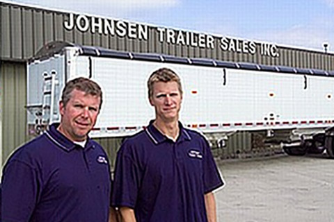 Travis and Rich stand by a trailer.